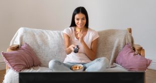 a woman sitting on a couch and watching tv